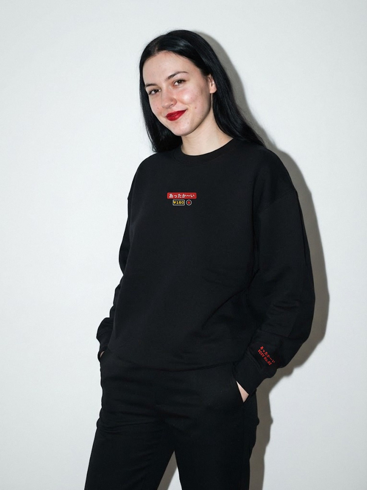 Model wearing the 5C5V Attaka-i あったか〜い heavyweight crewneck in Black, vending-machine button patch embroidered on the chest