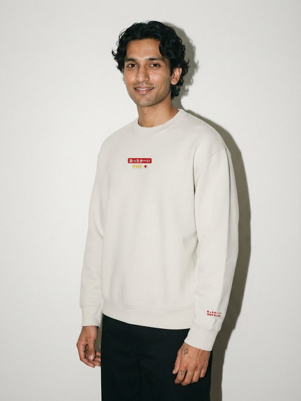 Model wearing the 5C5V Attaka-i あったか〜い heavyweight crewneck in Lunar Rock, vending-machine button patch embroidered on the chest