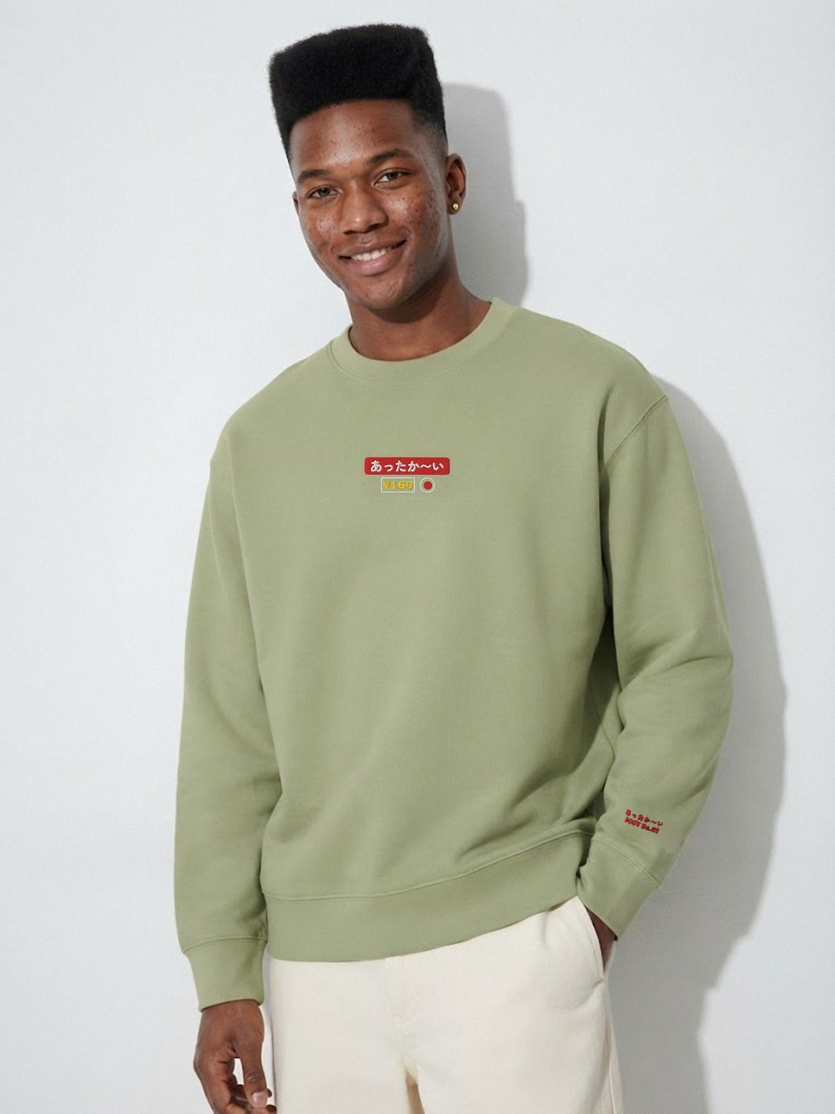 Model wearing the 5C5V Attaka-i あったか〜い heavyweight crewneck in Olive (Oil Green), vending-machine button patch embroidered on the chest