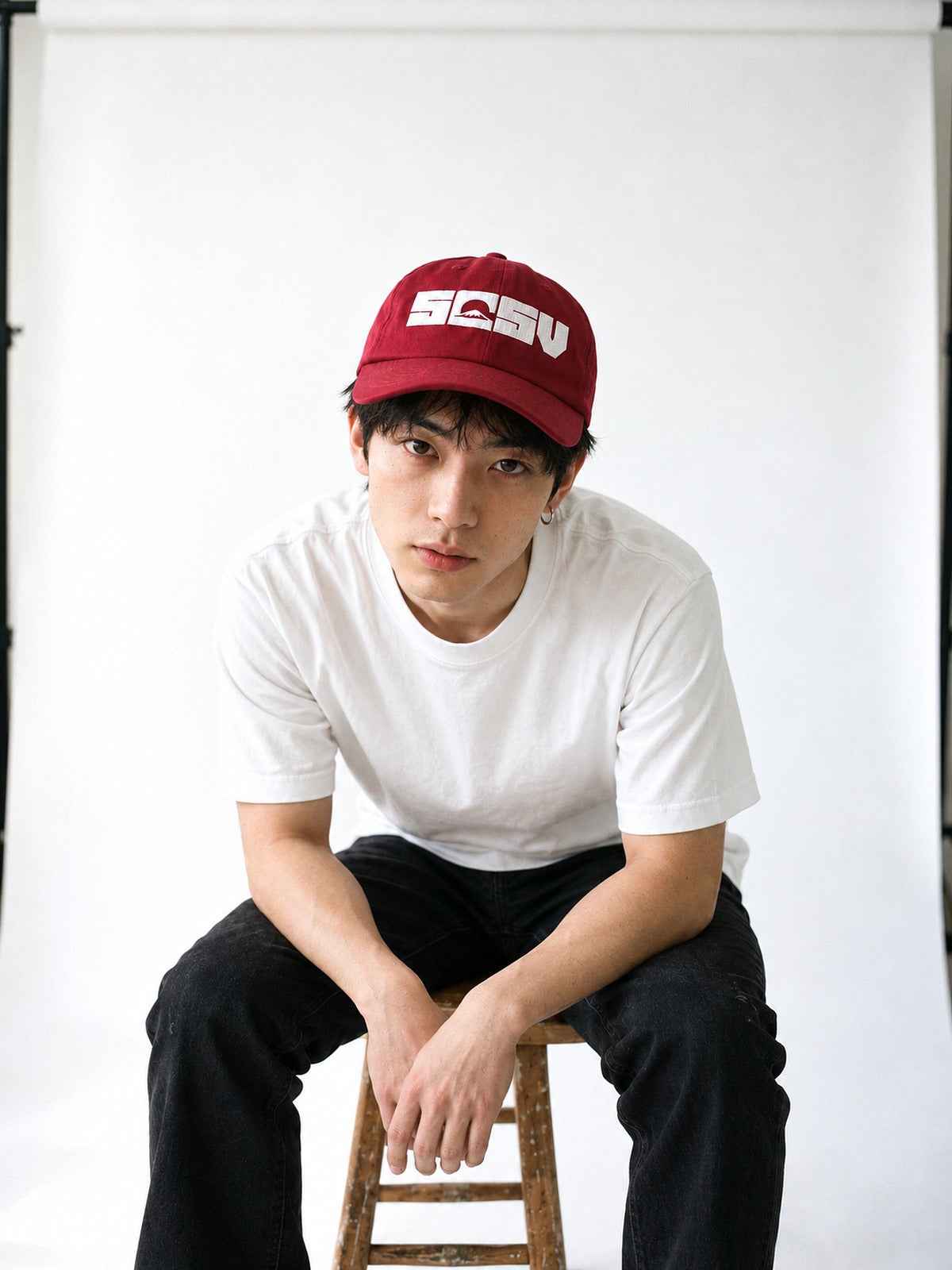 5C5V Originals Japanese baseball cap in cranberry with the white embroidered 5C5V Mt Fuji logo, worn with a white tee on a wooden stool against a white wall