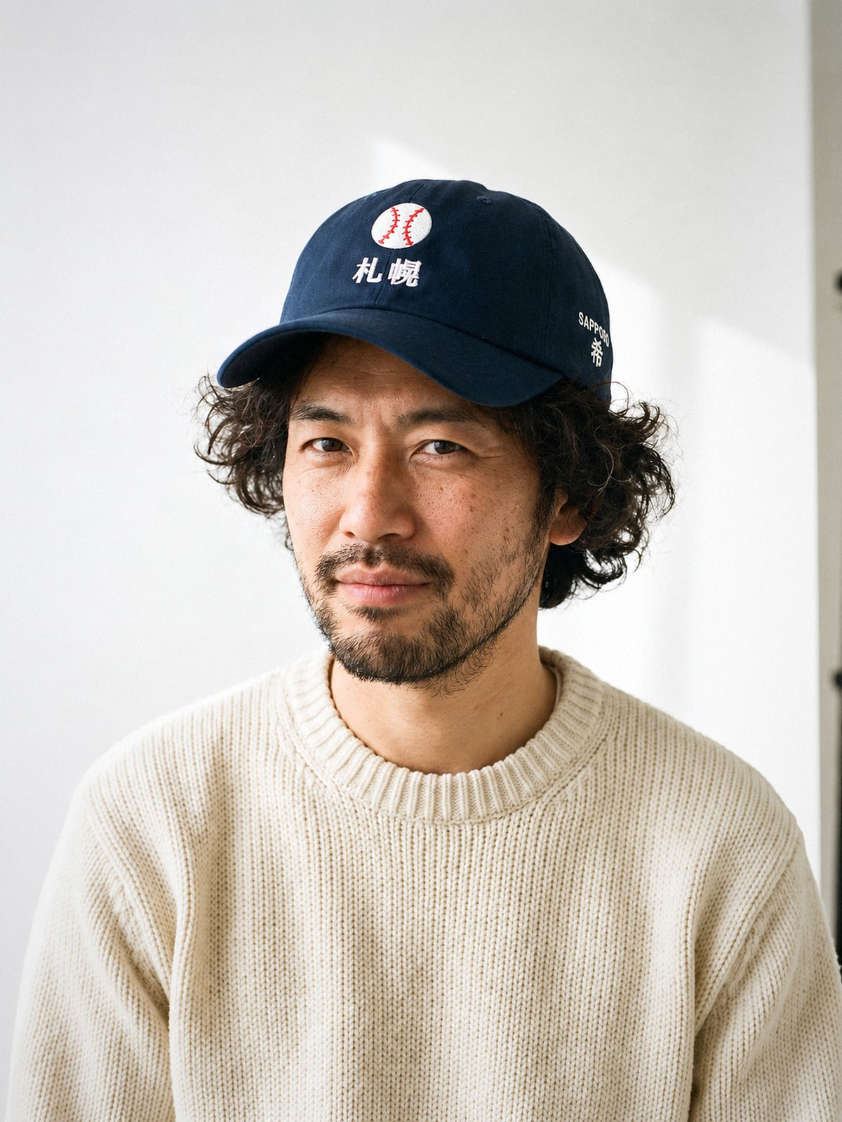Model wearing the 5C5V Sapporo Ball Japanese baseball cap in navy, a stitched baseball over 札幌 embroidered on the front, SAPPORO and 希 (hope) on the left side