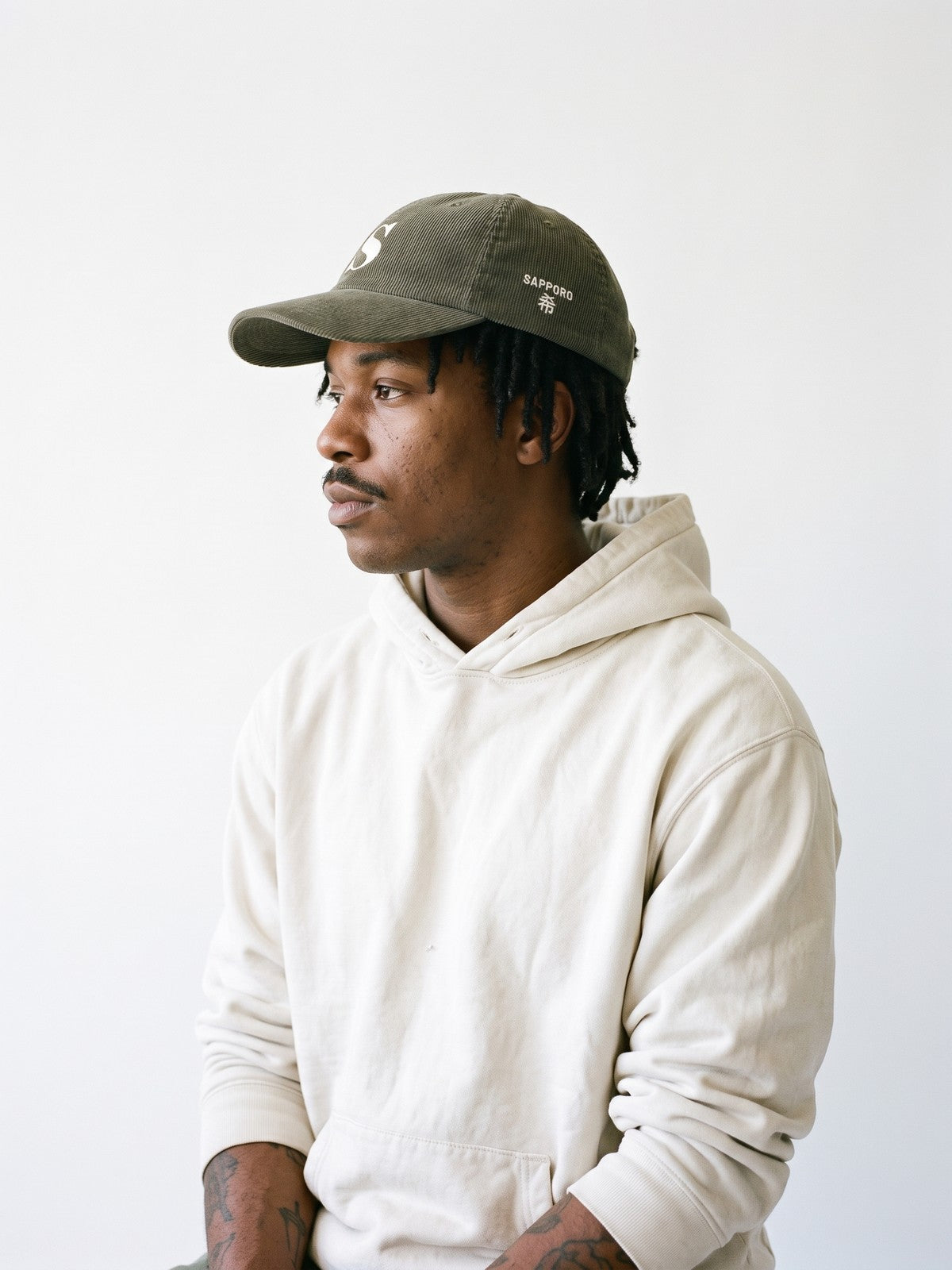 Side view of the 5C5V Sapporo S Corduroy Japanese baseball cap in olive, SAPPORO above 希 (hope) embroidered on the left side