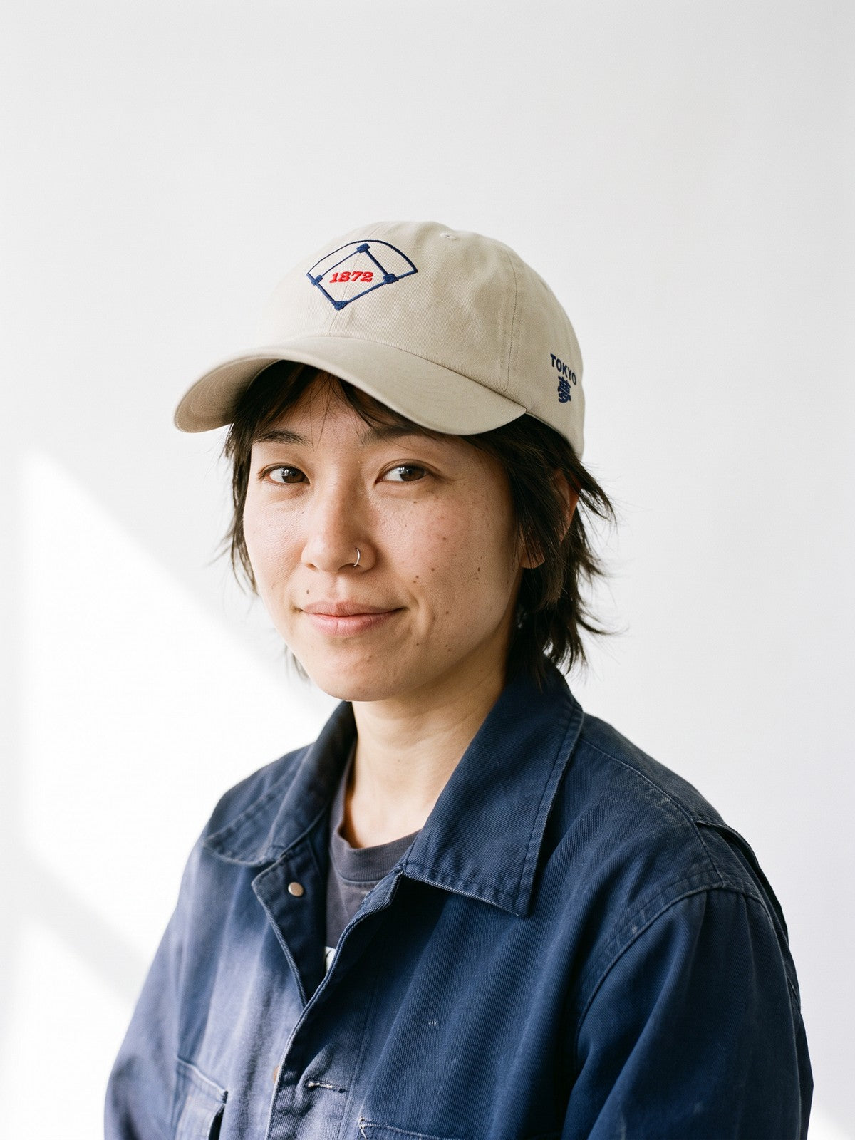 Model wearing the 5C5V Tokyo 1872 Japanese baseball cap in stone, a baseball diamond with 1872 embroidered on the front, TOKYO and 夢 (dream) on the left side