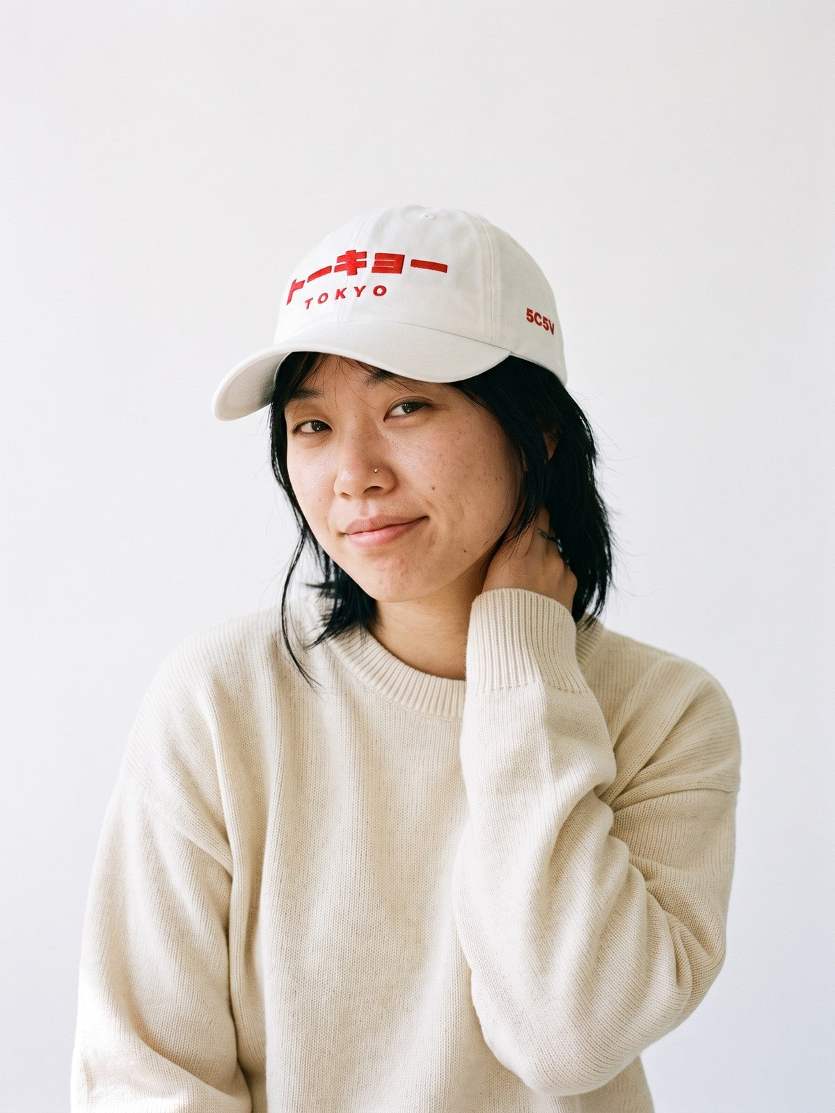 Model wearing the 5C5V Tokyo Katakana Japanese baseball cap in white, トーキョー over TOKYO embroidered in red on the front, 5C5V in red on the left side