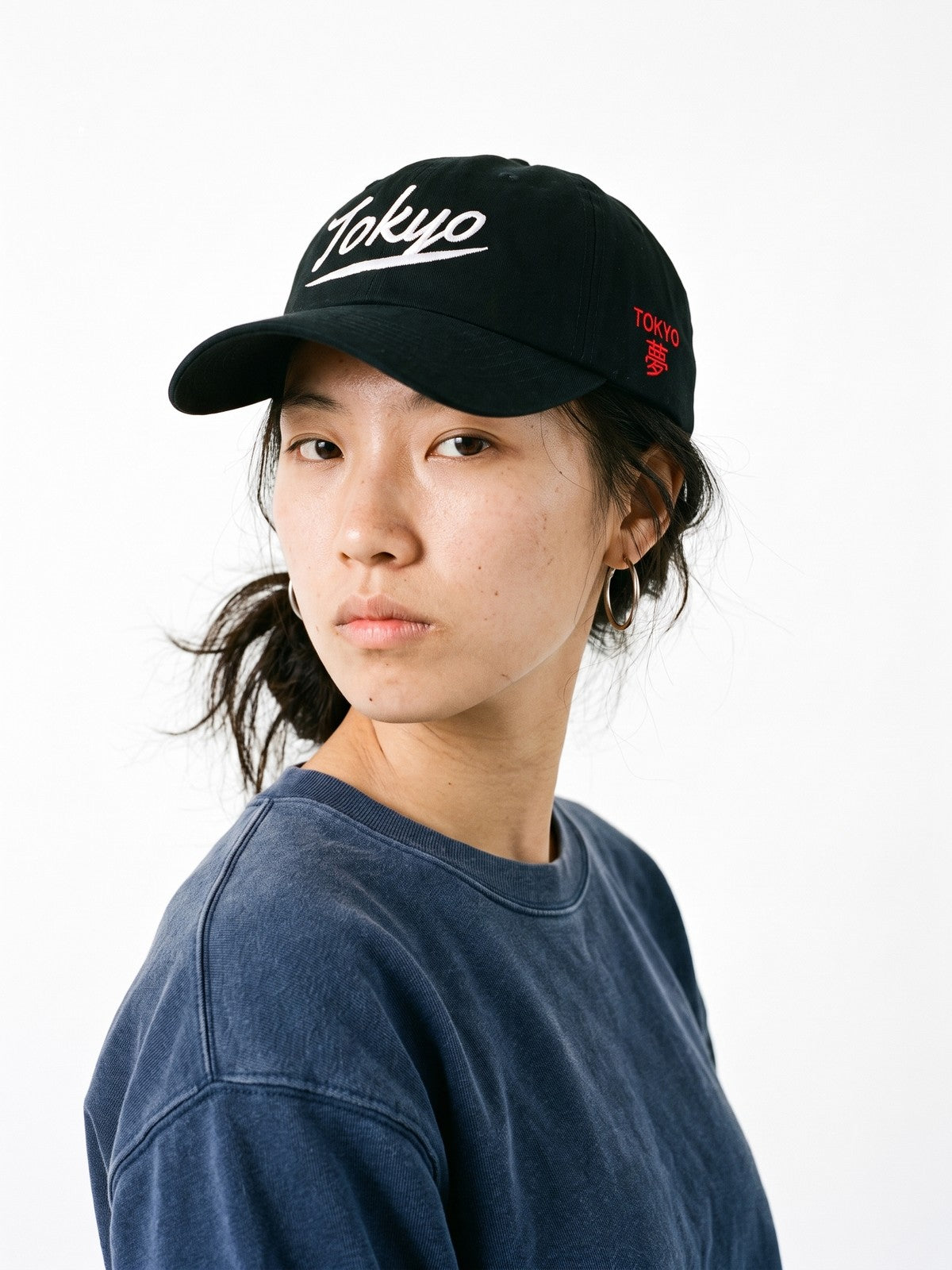 Model wearing the 5C5V Tokyo Script Japanese baseball cap in black, Tokyo in ballclub script embroidered on the front, TOKYO and 夢 (dream) on the left side