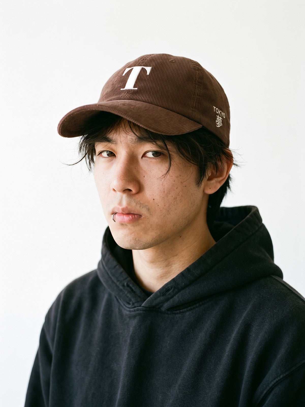 Model wearing the 5C5V Tokyo T Corduroy Japanese baseball cap in brown, a serif T embroidered on the front, TOKYO and 夢 (dream) on the left side