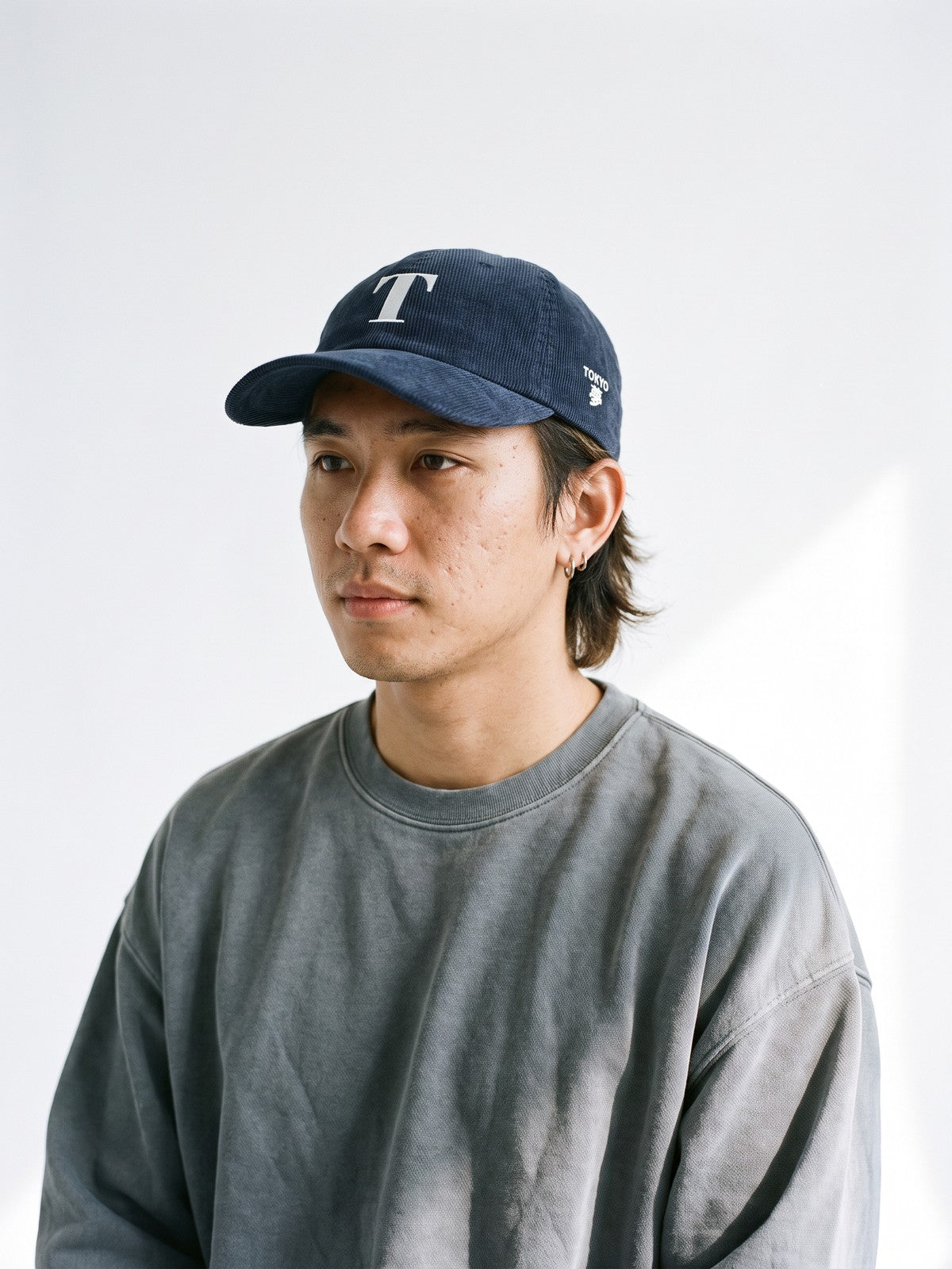 Model wearing the 5C5V Tokyo T Corduroy Japanese baseball cap in navy, a serif T embroidered on the front, TOKYO and 夢 (dream) on the left side