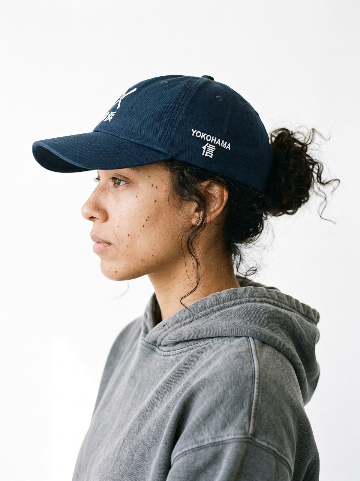 Side view of the 5C5V Yokohama Crossed Bats Japanese baseball cap in navy, YOKOHAMA above 信 (trust) embroidered on the left side