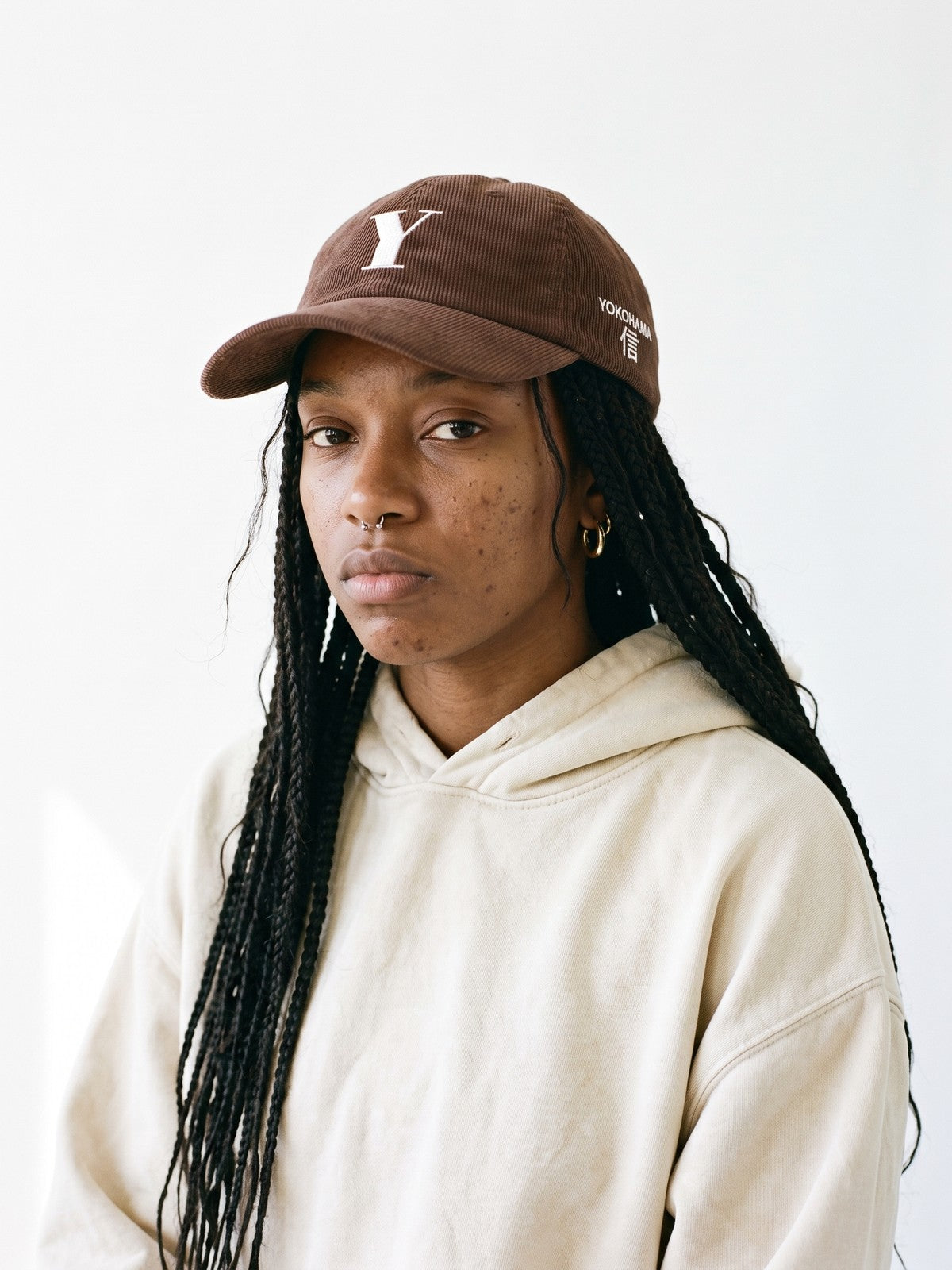 Model wearing the 5C5V Yokohama Y Corduroy Japanese baseball cap in brown, a serif Y embroidered on the front, YOKOHAMA and 信 (trust) on the left side