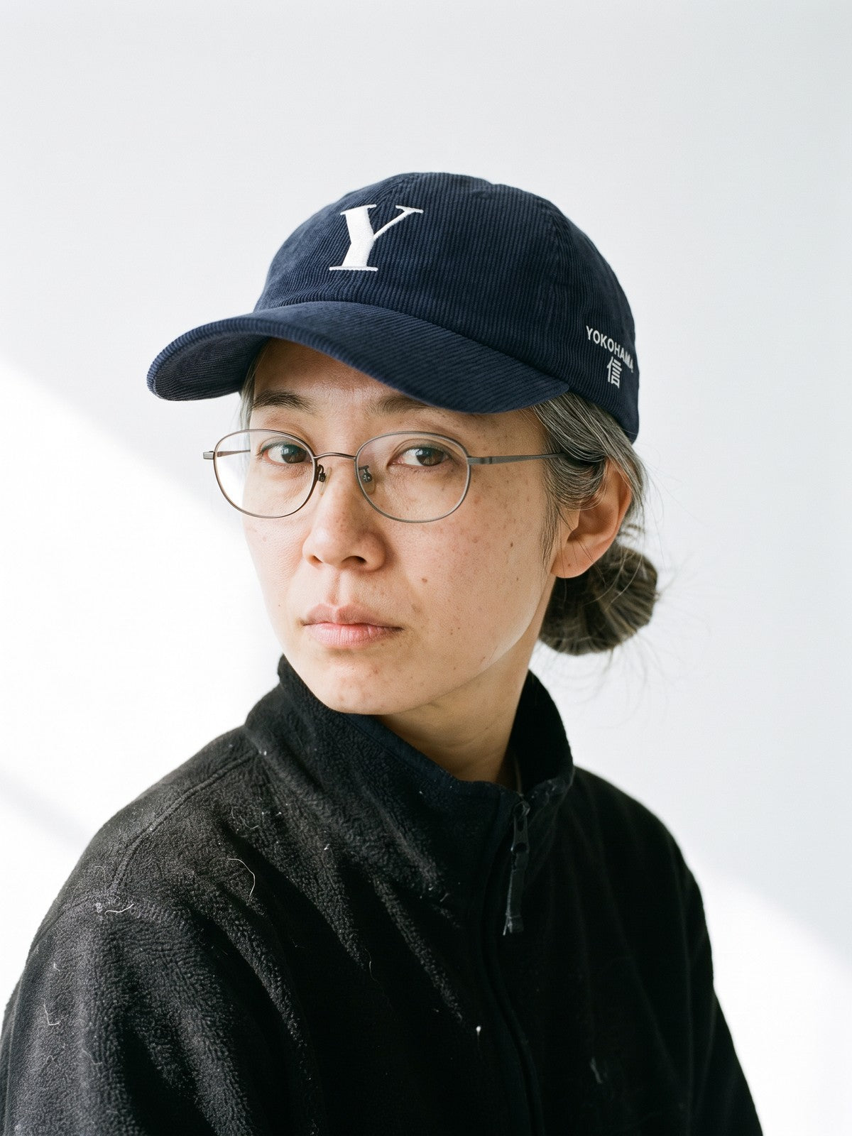 Model wearing the 5C5V Yokohama Y Corduroy Japanese baseball cap in navy, a serif Y embroidered on the front, YOKOHAMA and 信 (trust) on the left side