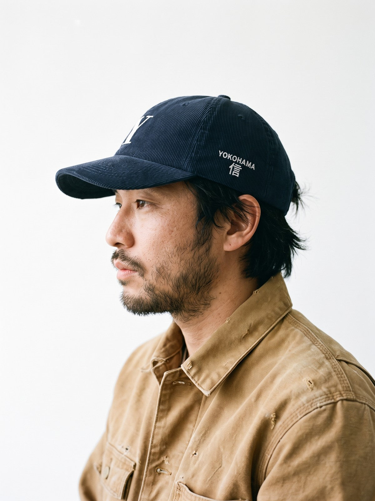 Side view of the 5C5V Yokohama Y Corduroy Japanese baseball cap in navy, YOKOHAMA above 信 (trust) embroidered on the left side