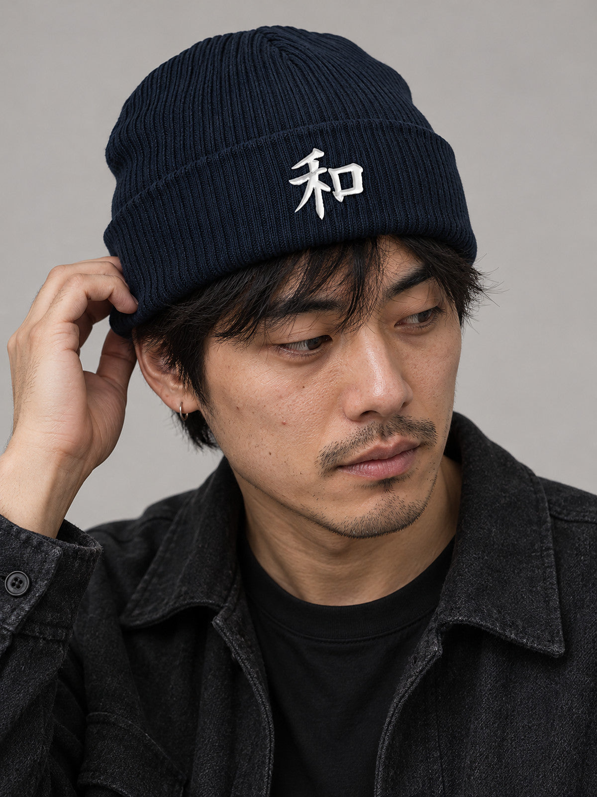 Close studio shot of a model adjusting the cuff of the Oxford Navy Kyoto Harmony 和 ribbed beanie