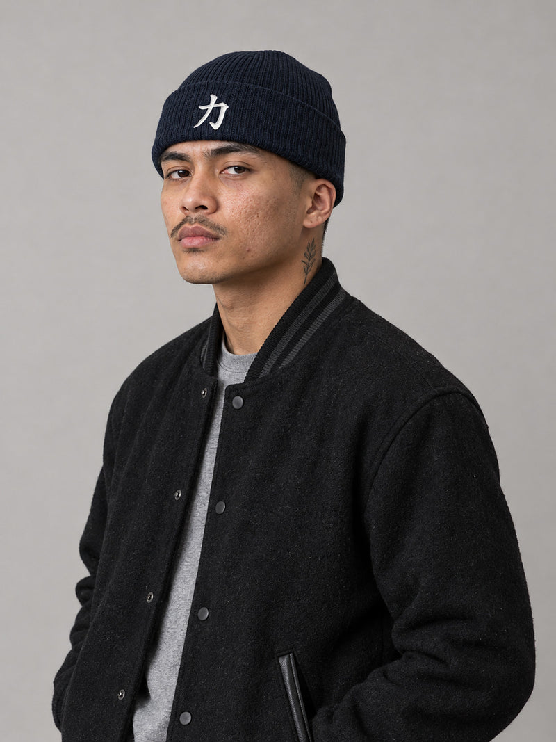 Model wearing the Oxford Navy Osaka Strength 力 ribbed beanie in the studio, white 3D-puff 力 embroidered on the cuff
