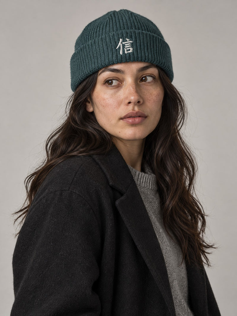 Model wearing the Petrol Blue Yokohama Trust 信 fisherman beanie in the studio, white satin-stitch 信 embroidered on the cuff