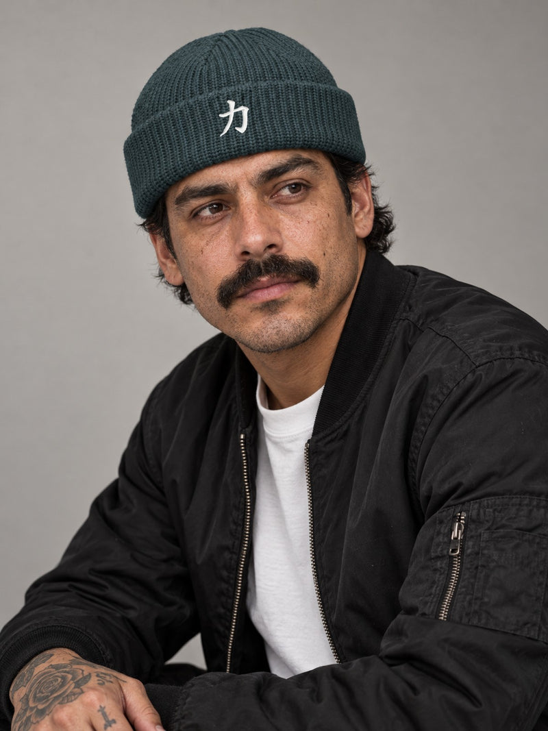Model wearing the Petrol Blue Osaka Strength 力 fisherman beanie in the studio, white satin-stitch 力 embroidered on the cuff