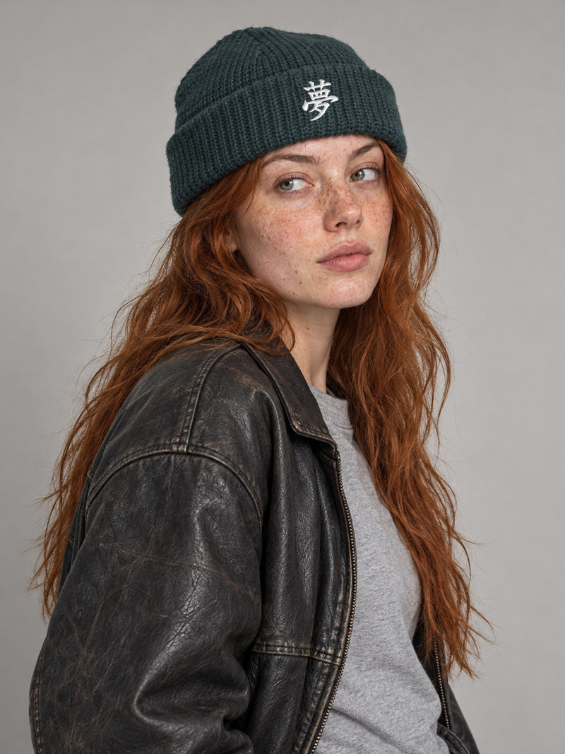 Model wearing the Petrol Blue Tokyo Dream 夢 fisherman beanie in the studio, white satin-stitch 夢 embroidered on the cuff