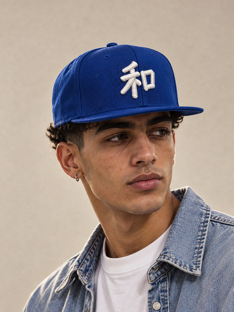 Model wearing the royal blue Kyoto Harmony 和 Japanese Snapback, white 3D-puff 和 on the front