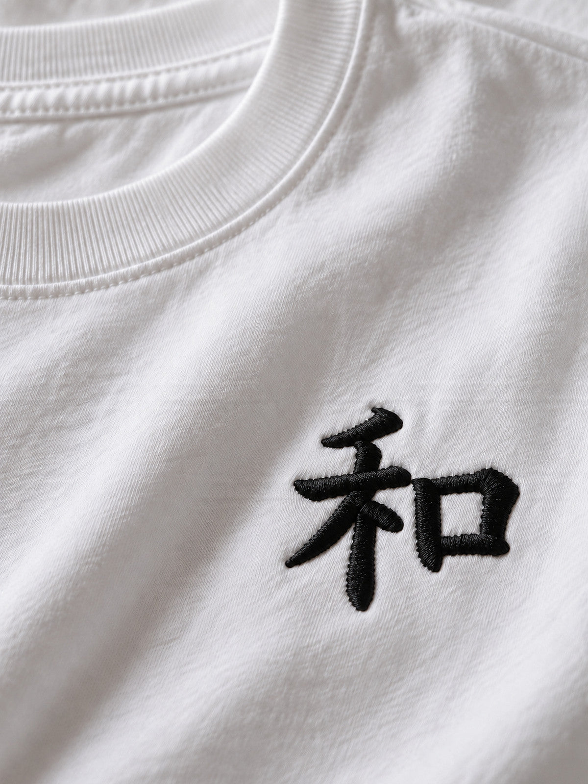 Close-up of the black 和 chest embroidery on the white Kyoto Harmony premium oversized tee
