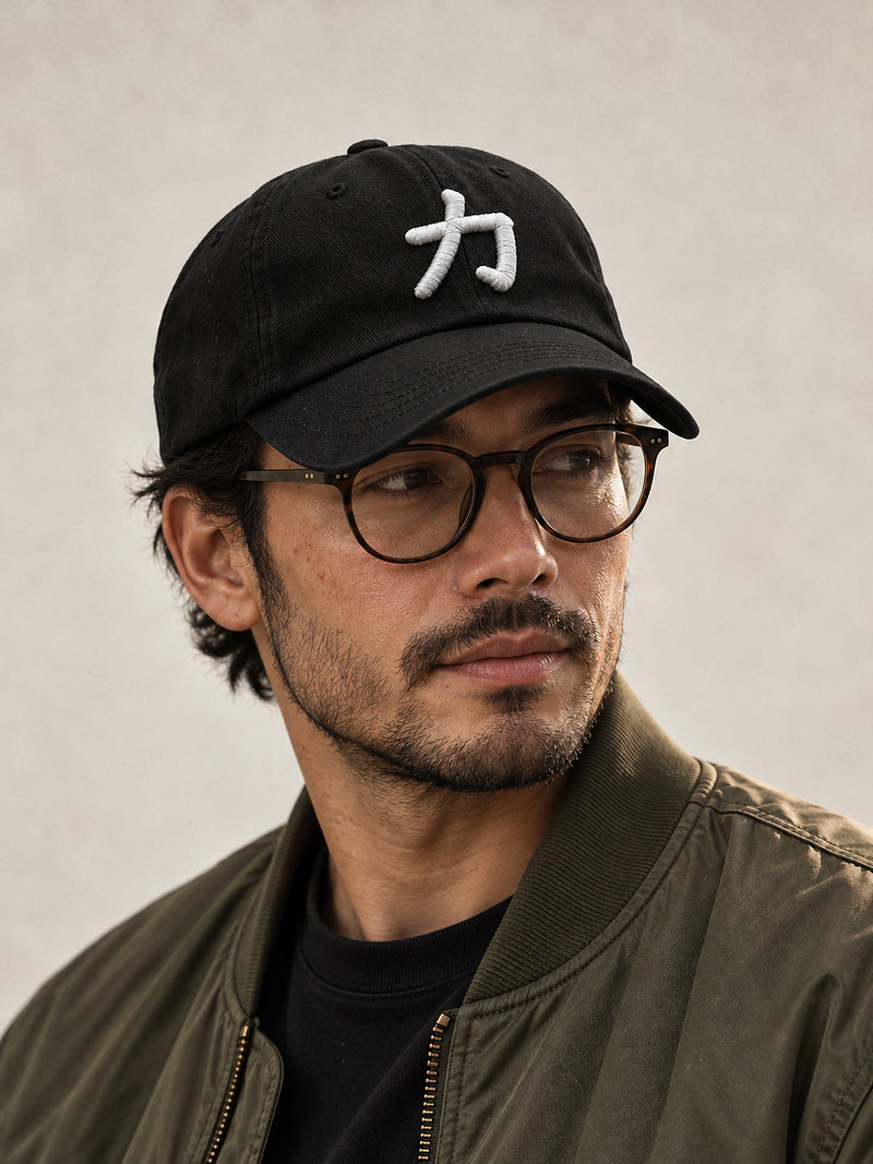 Model wearing the black Osaka Strength 力 Japanese Baseball Cap pulled low, white 3D-puff 力 on the front