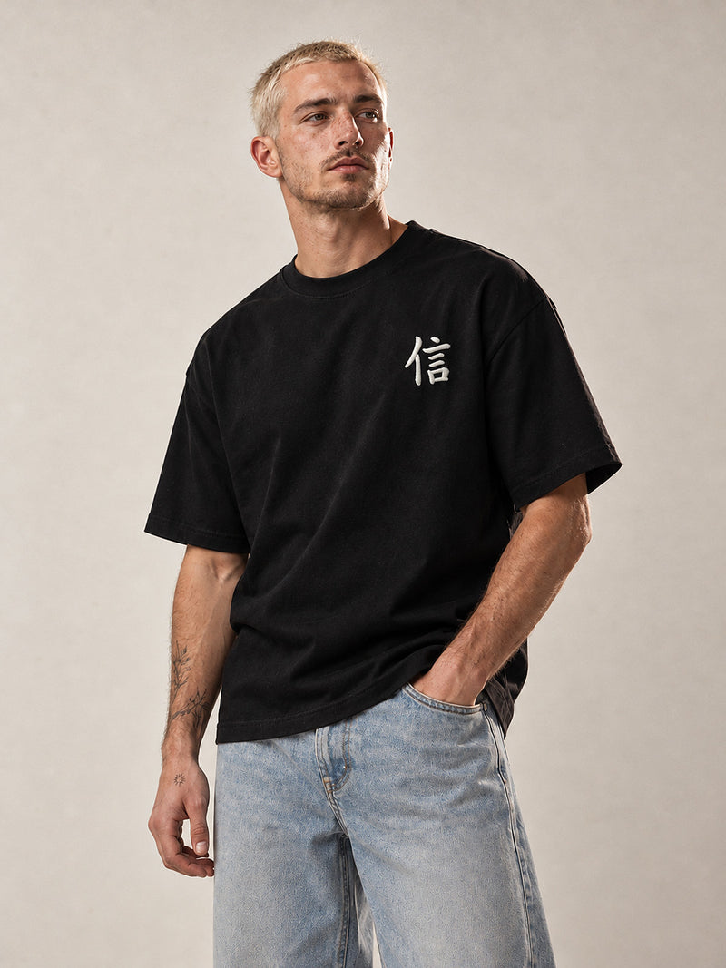 Model wearing the black Yokohama Trust 信 premium oversized tee, front view with the white 信 kanji embroidered on the chest
