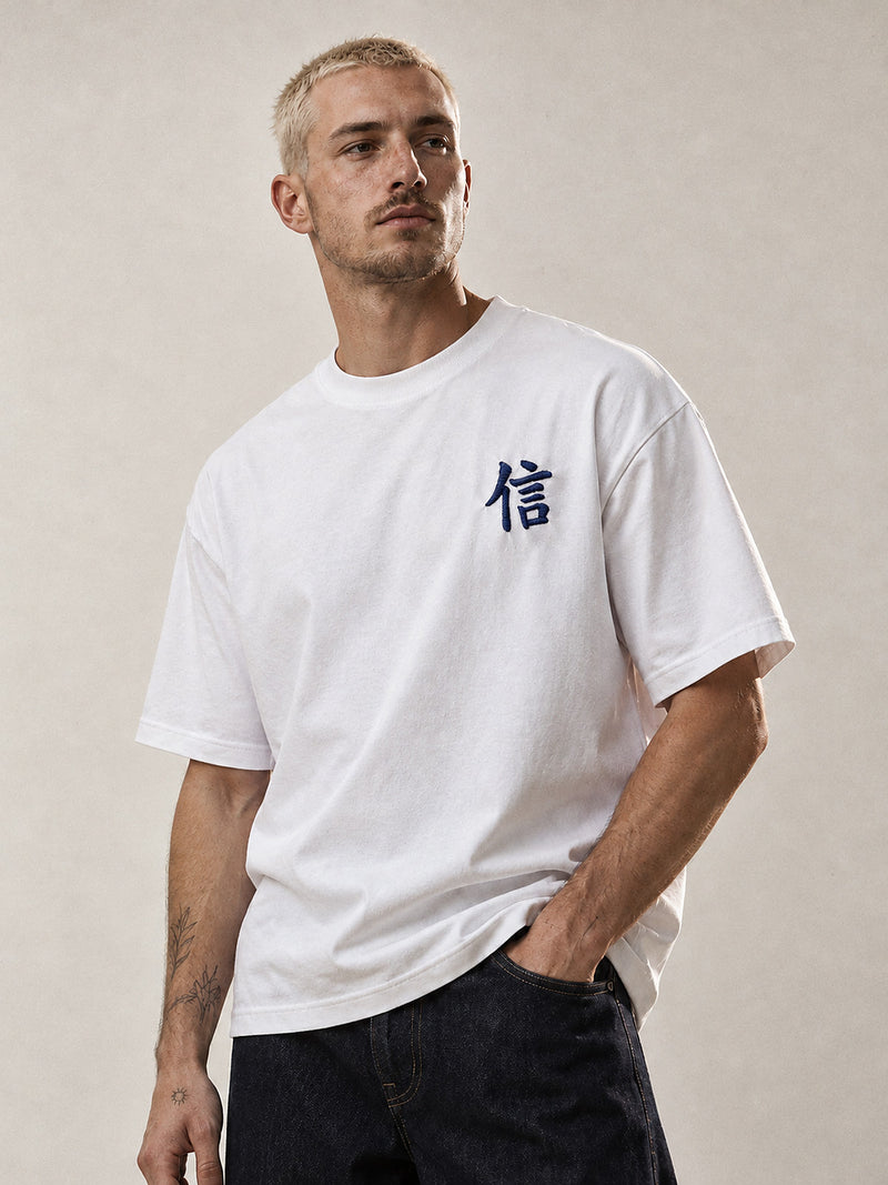 Model wearing the white Yokohama Trust 信 premium oversized tee, front view with the navy 信 kanji embroidered on the chest