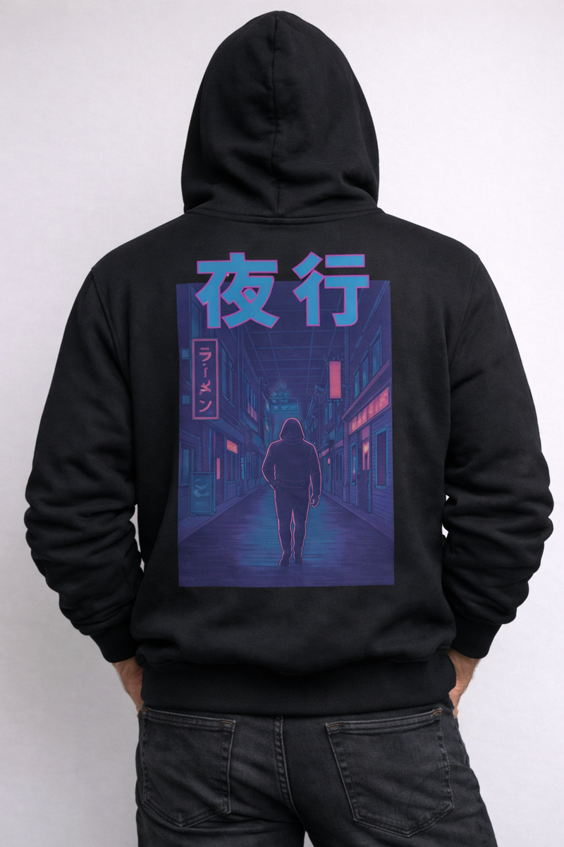 Model in the black Radiant Dawn hoodie, hood up, back print of a lone figure on a neon street with 夜行 (night journey)
