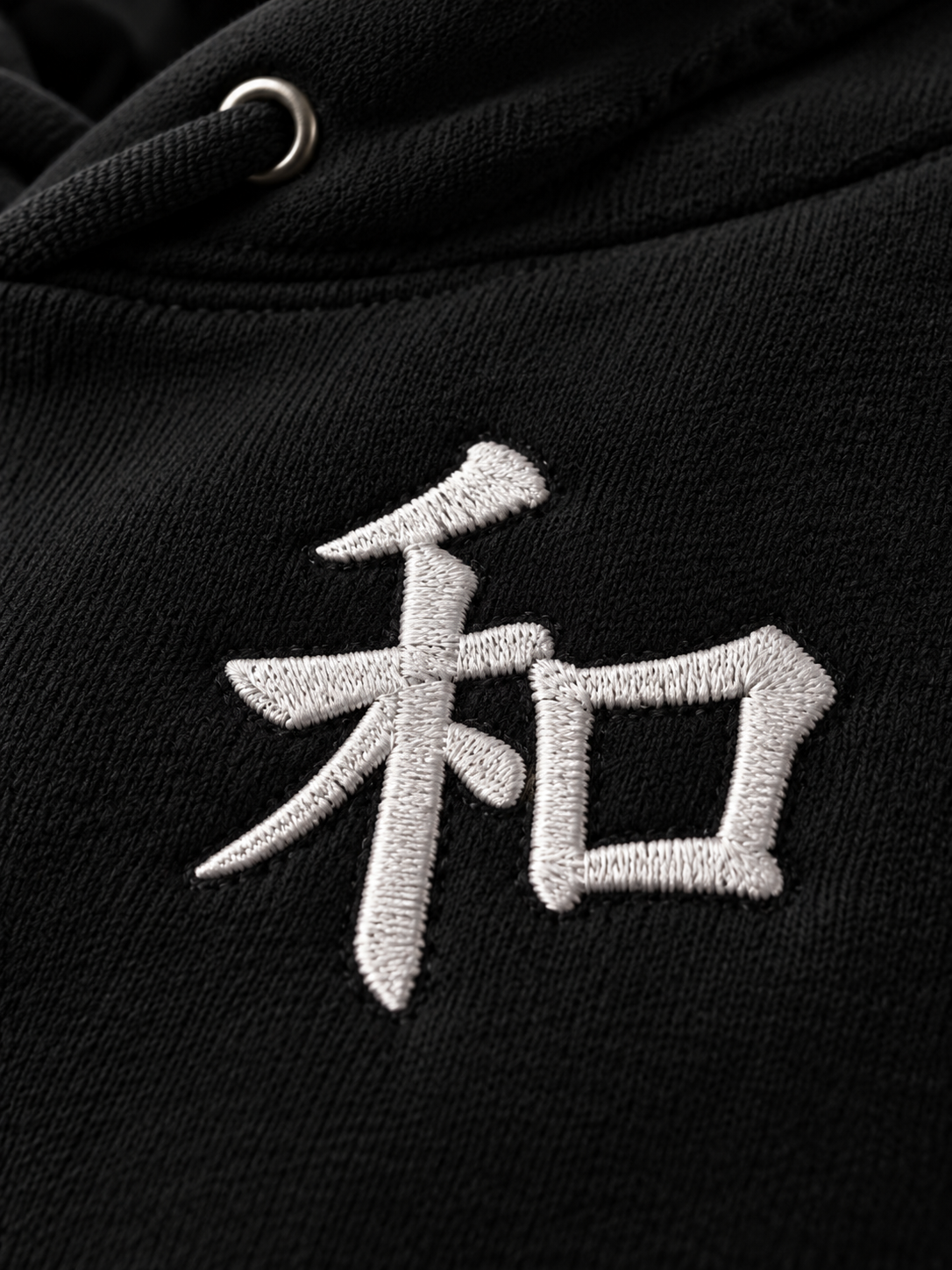 Close-up of the white satin-stitch 和 embroidery on the black Kyoto Harmony 和 hoodie