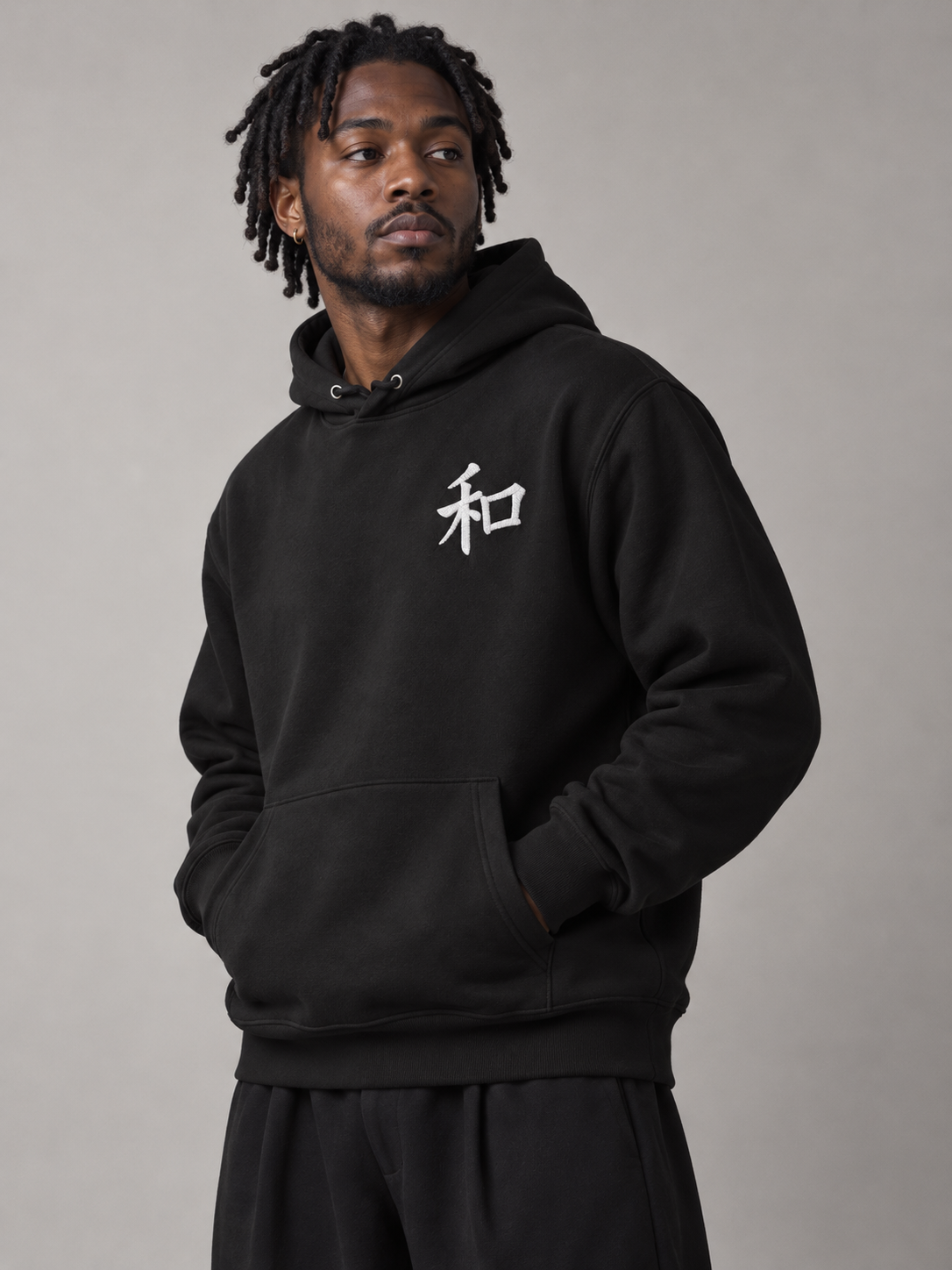 Model wearing the black Kyoto Harmony 和 hoodie in the studio, small white embroidered 和 on the left chest