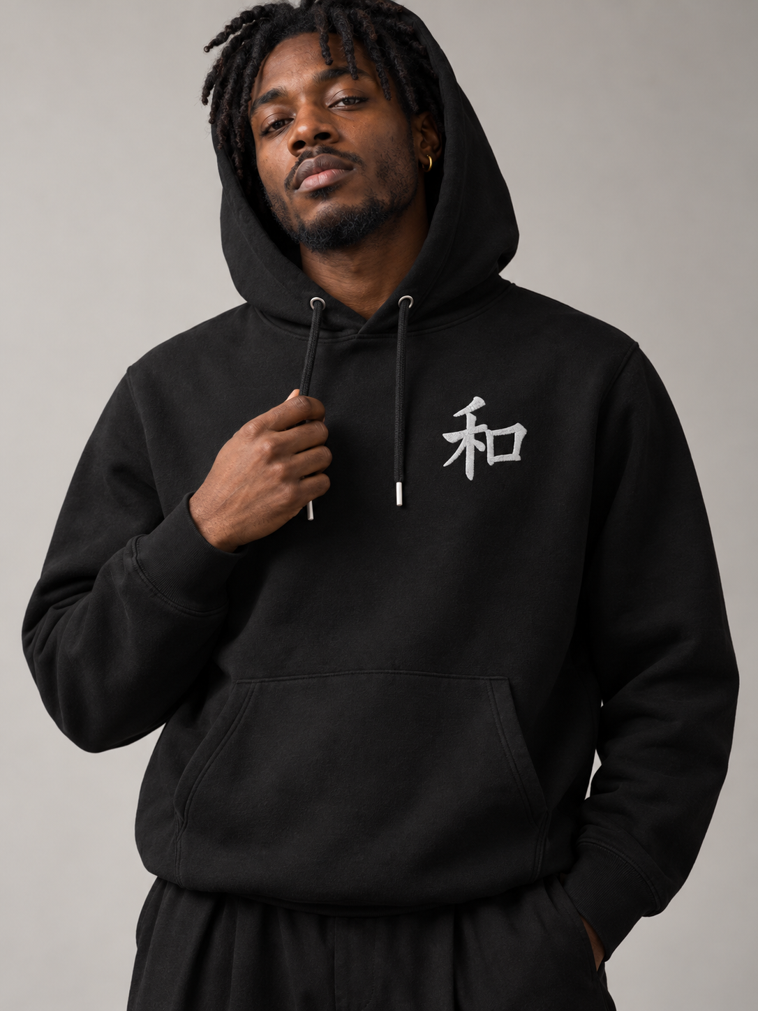 Model in the black Kyoto Harmony 和 hoodie with the hood up, studio shot