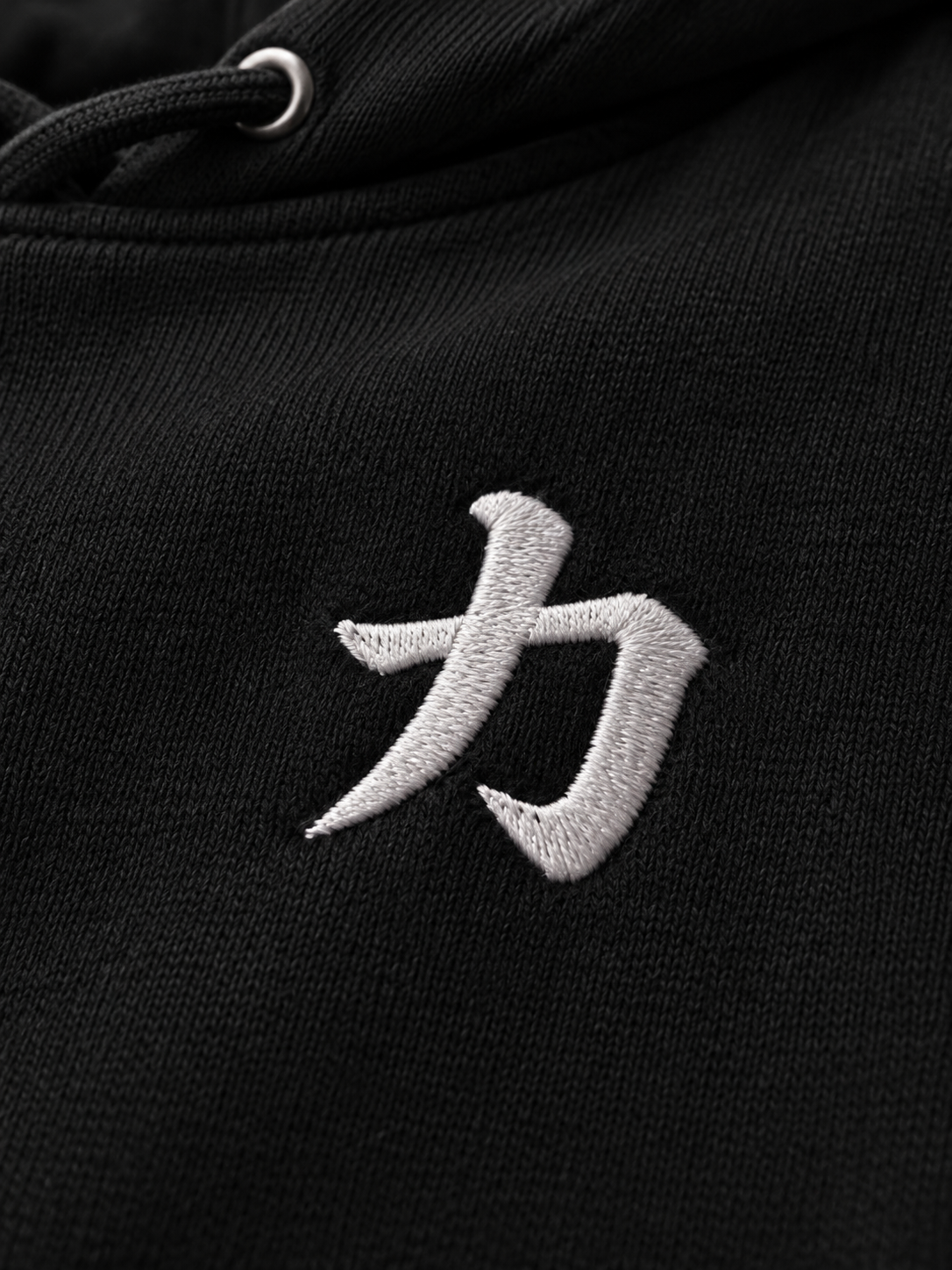 Close-up of the white satin-stitch 力 embroidery on the black Osaka Strength 力 hoodie