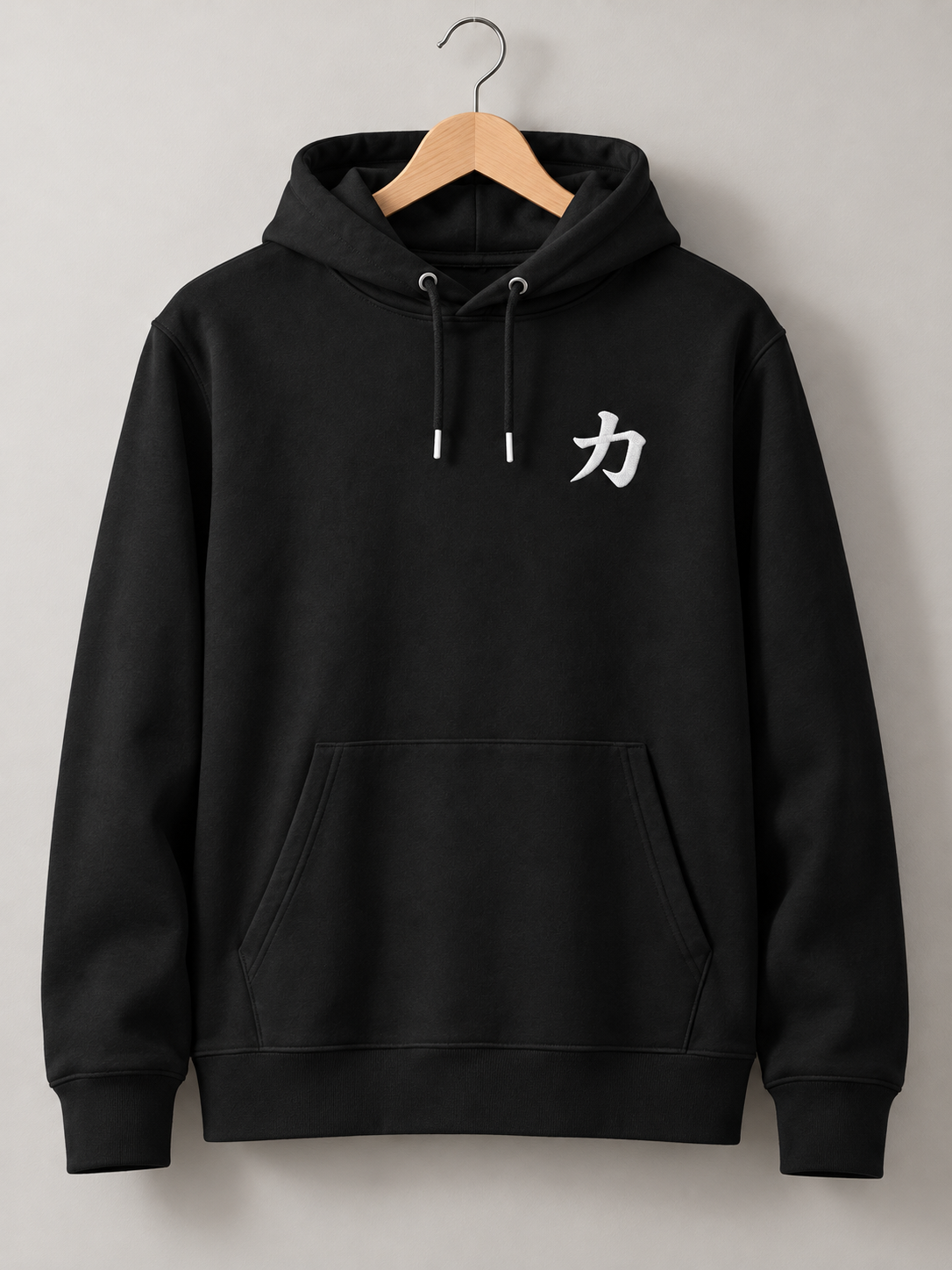 Black Osaka Strength 力 hoodie on a wooden hanger, front view with the small white embroidered 力 on the left chest