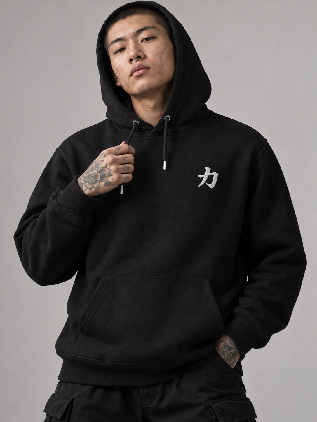 Model in the black Osaka Strength 力 hoodie with the hood up, studio shot