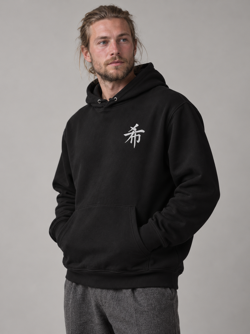 Model wearing the black Sapporo Hope 希 hoodie in the studio, small white embroidered 希 on the left chest