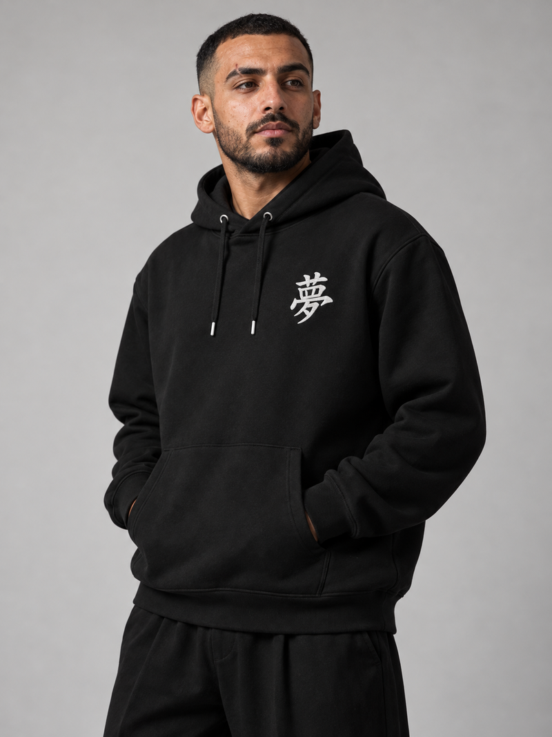 Model wearing the black Tokyo Dream 夢 hoodie in the studio, small white embroidered 夢 on the left chest
