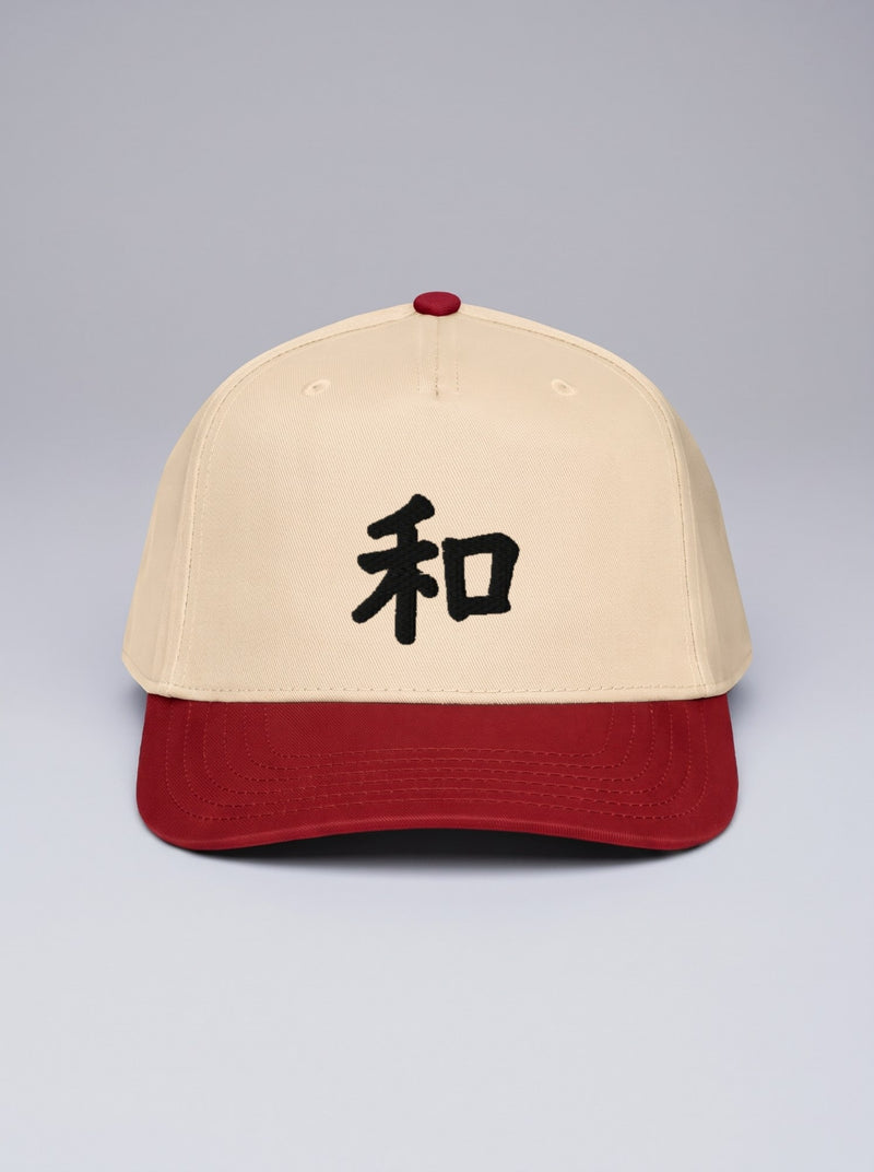 Kyoto Harmony 和 5-panel cap, natural crown with red visor, front view — black embroidered kanji on a grey studio backdrop