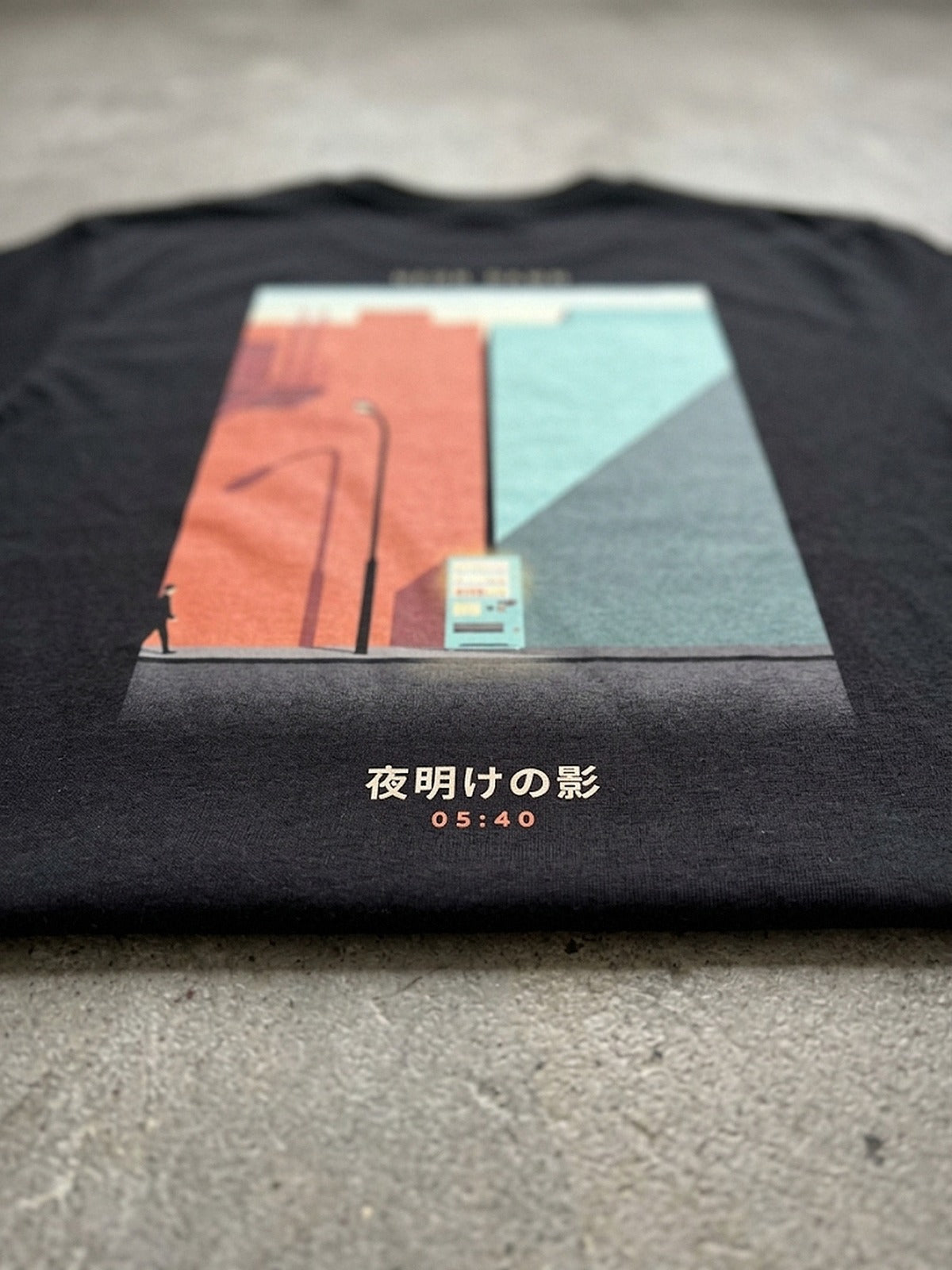 Detail of the Neon Dawn Kage 影 back print on heavyweight black cotton, the long dawn shadows and the 夜明けの影 caption in focus