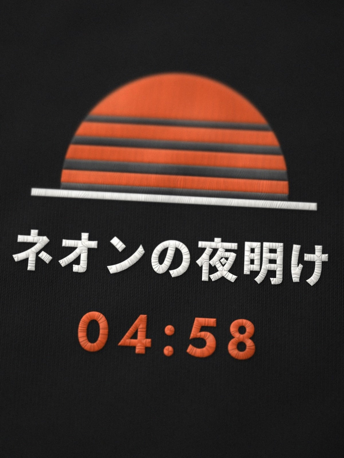 Close-up of the embroidered Neon Dawn sun on the Shihatsu 始発 black tee, ネオンの夜明け and 04:58 stitched in orange and white thread