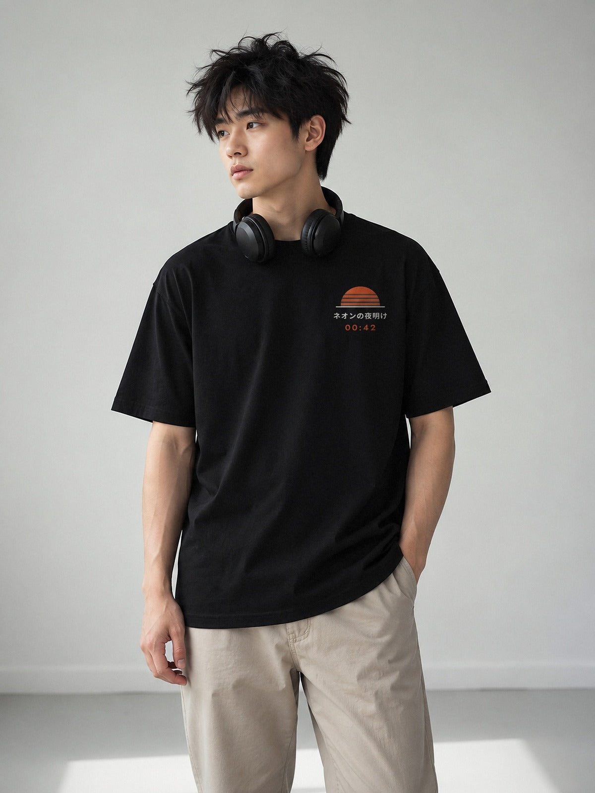 Model wearing the Shūden black tee from the front, with the Neon Dawn sun and 00:42 embroidered on the left chest