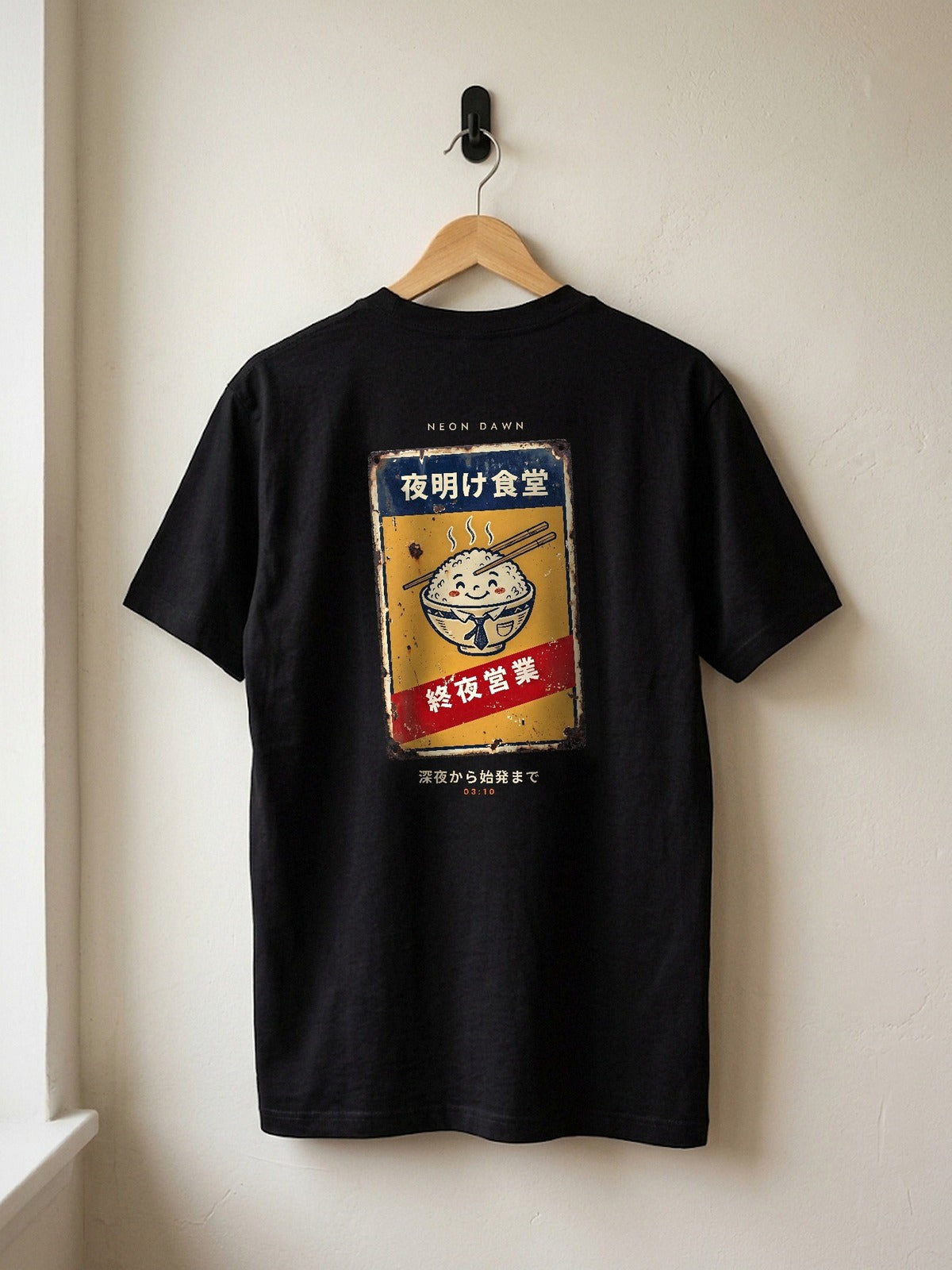 Neon Dawn Shuya Eigyo 終夜営業 heavyweight black tee on a wooden hanger against a plaster wall, showing the open-all-night Tokyo diner sign back print