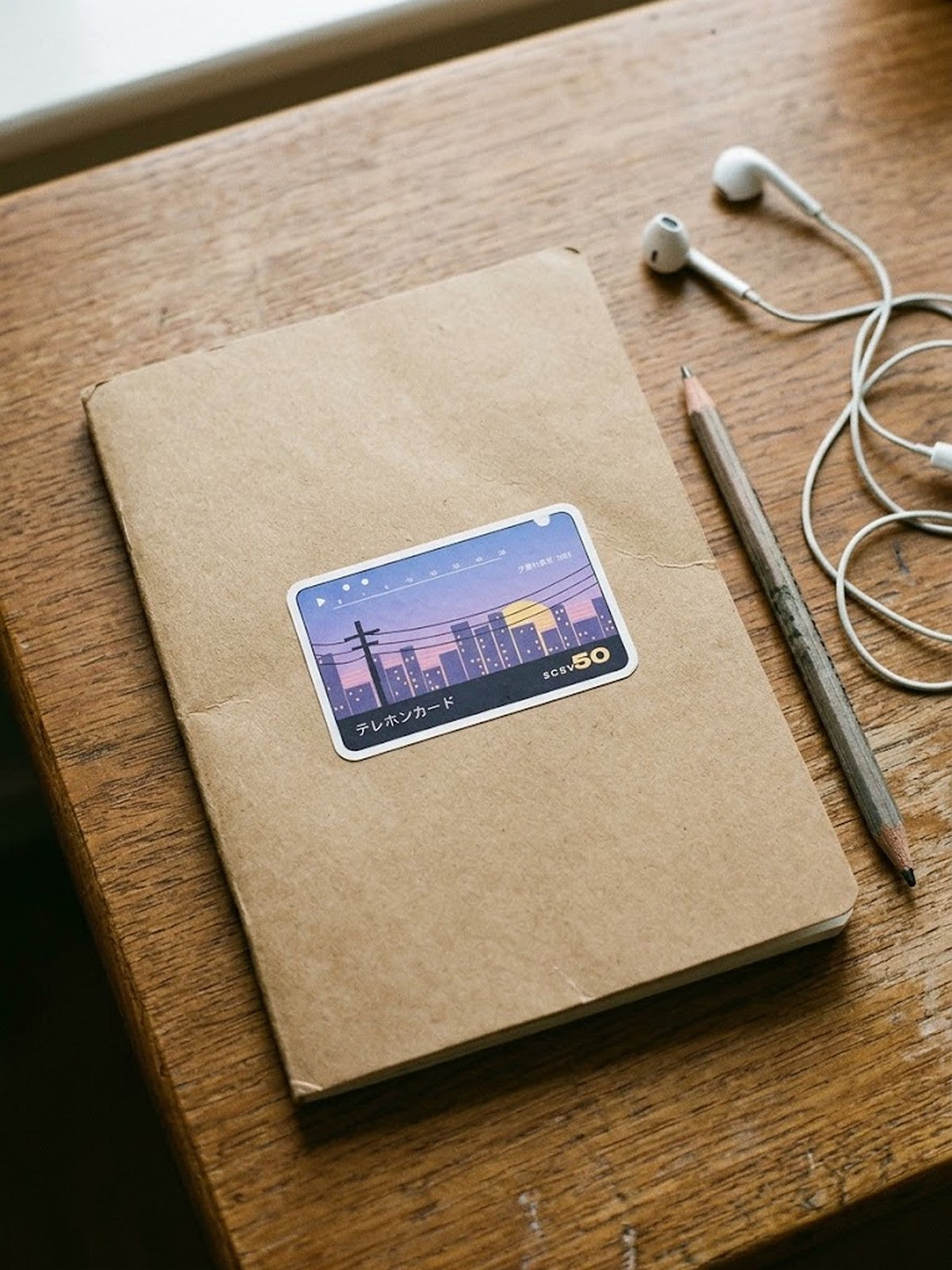Terehon Kādo テレホンカード Japanese Phone Card Sticker by 5C5V on a kraft notebook with a pencil and earphones