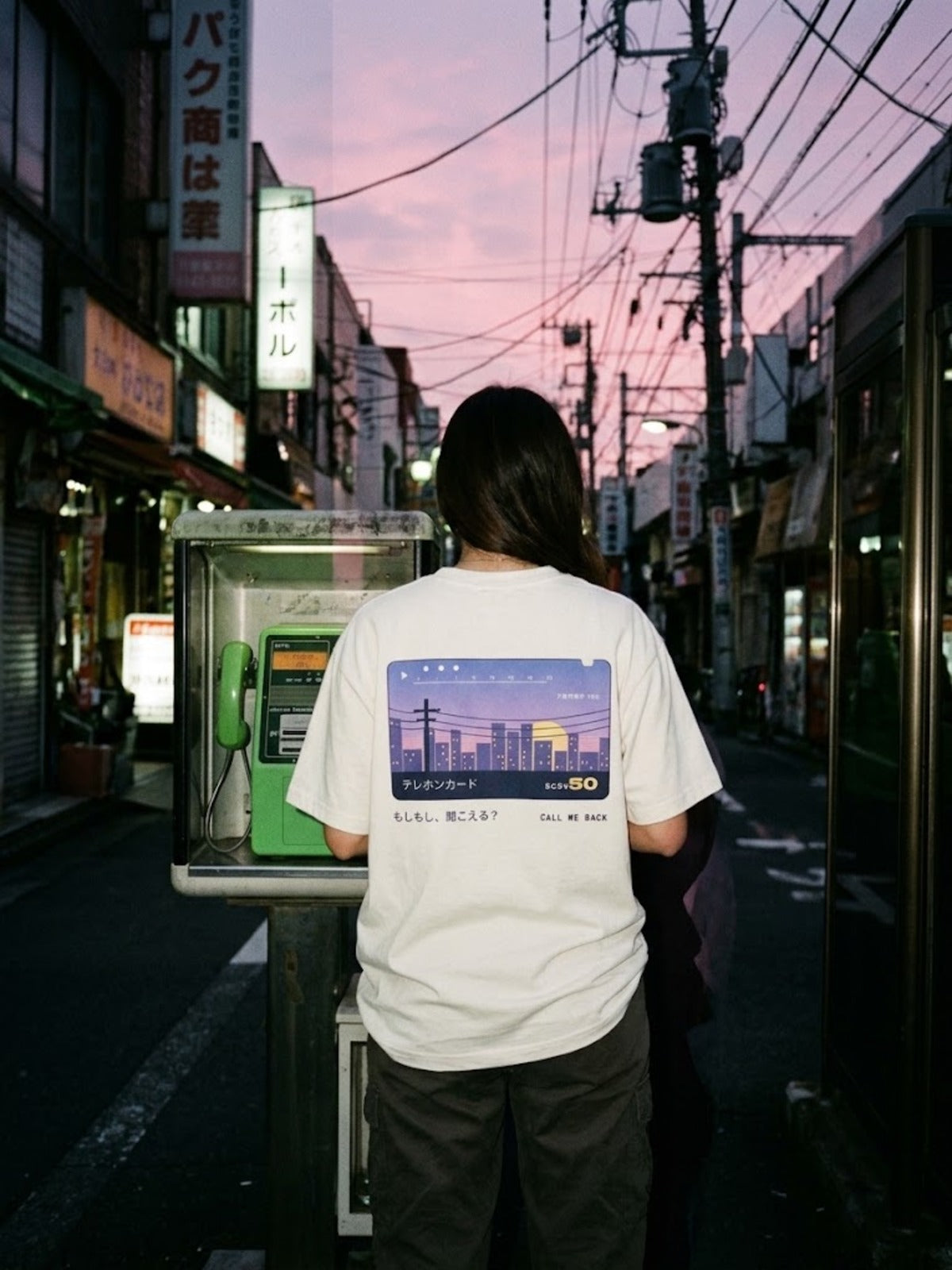 Terehon Kādo テレホンカード Japanese Phone Card T-Shirt by 5C5V worn beside a green phone box at dusk