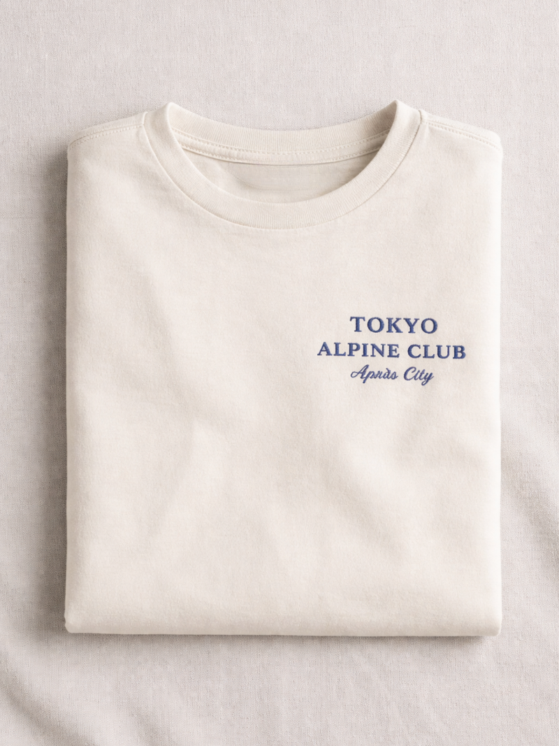 Vintage white Tokyo Alpine Club tee folded, showing the navy Tokyo Alpine Club chest print
